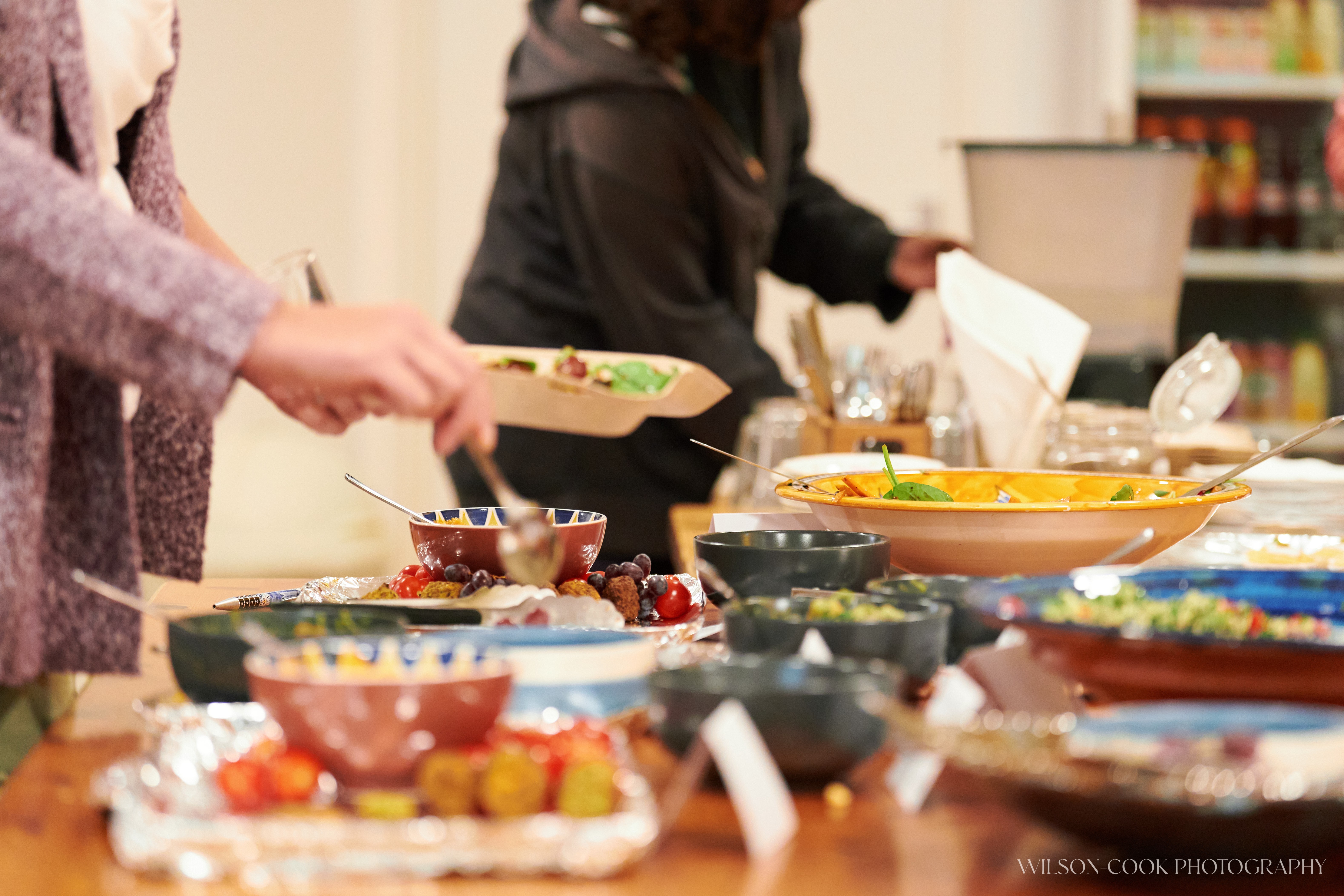 2025.  A table full of food, with two people serving themselves using serving spoons.
