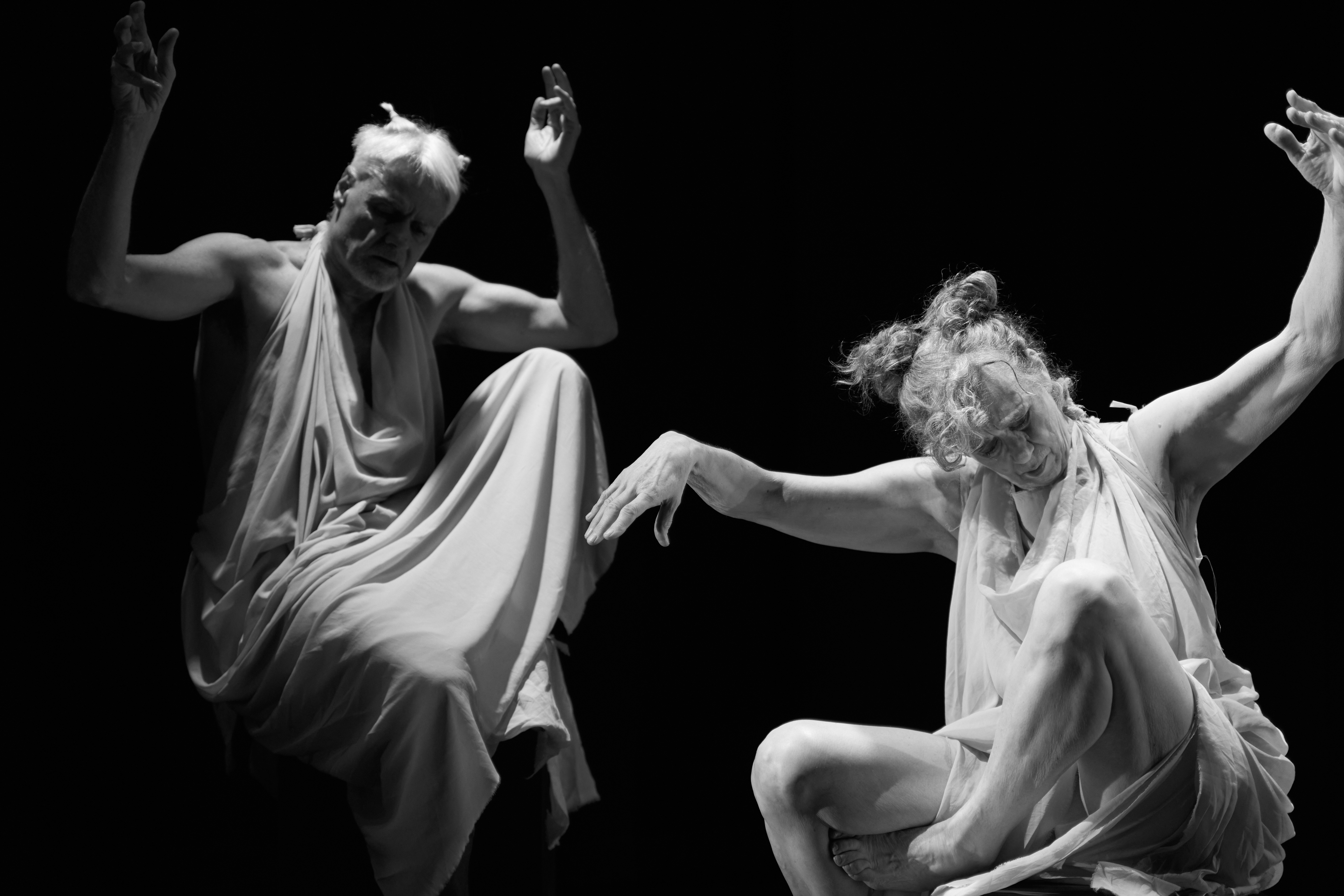 2026.  A black and white image of two dancers on stage, they are wearing toga-like garments and are positioned as statues.